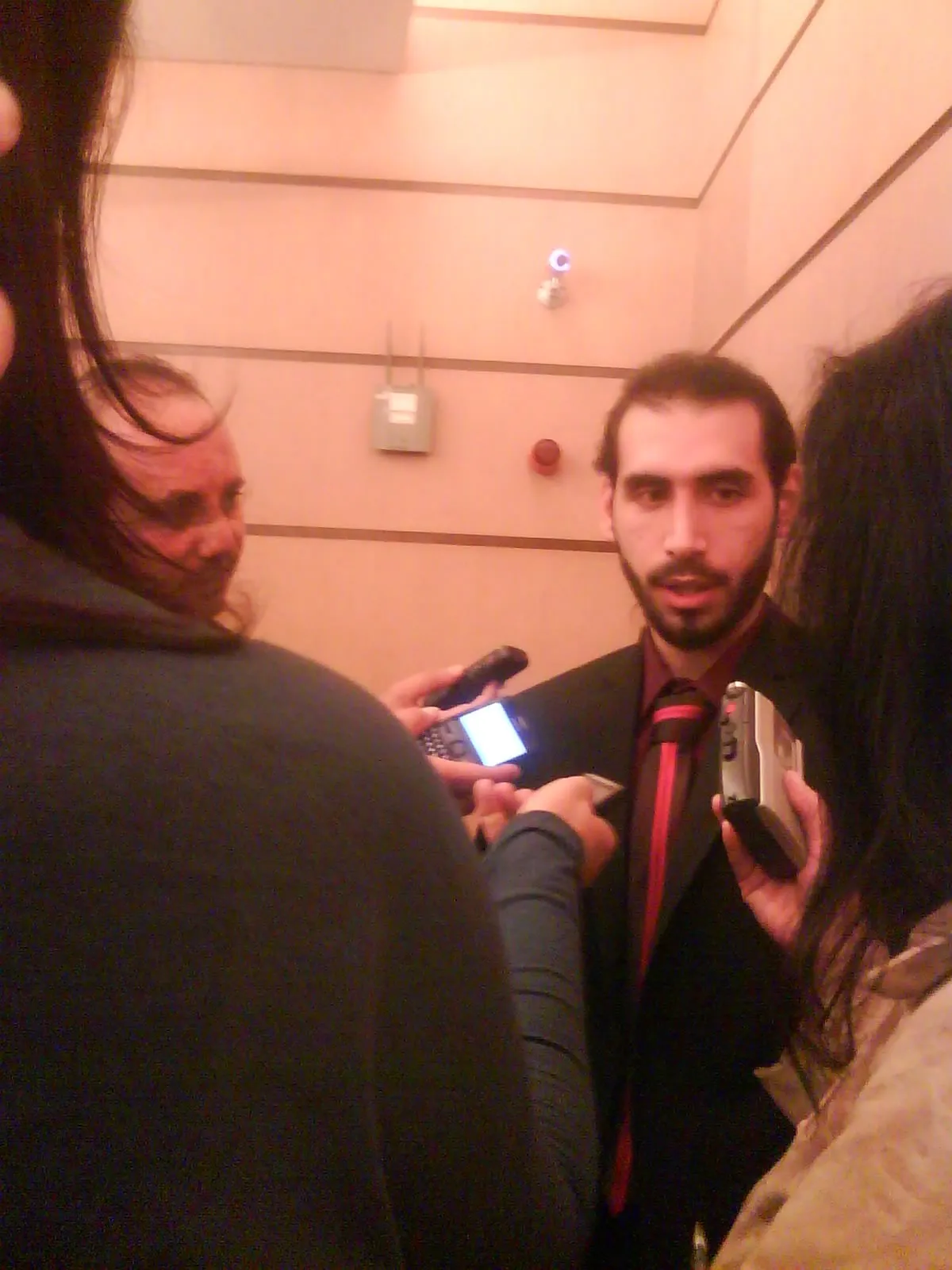 Molham Mahmoud answering questions from a group of journalists holding voice recorders