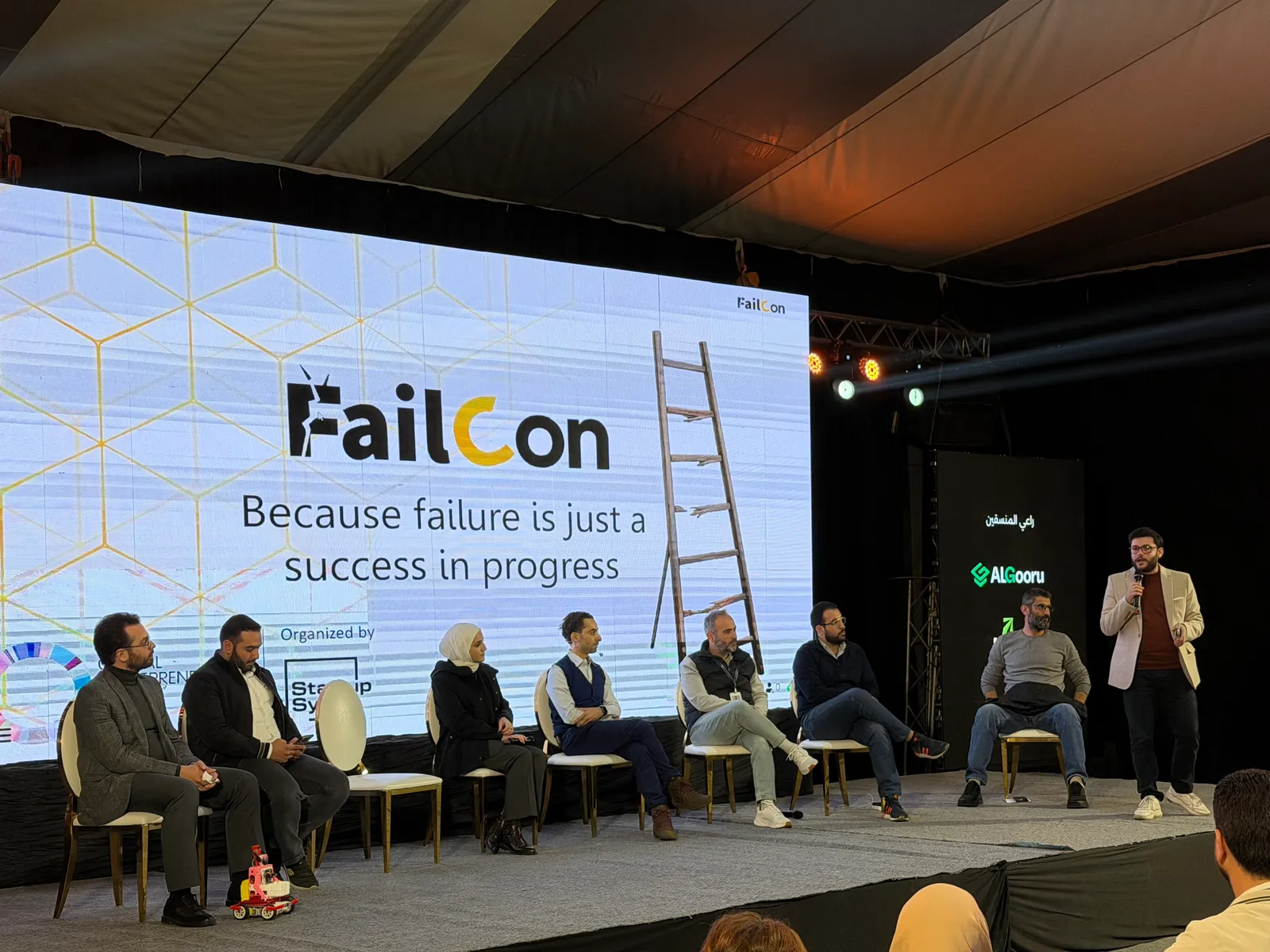 The FailCon stage in Damascus, speakers seated in front of a screen reading Because failure is just a success in progress