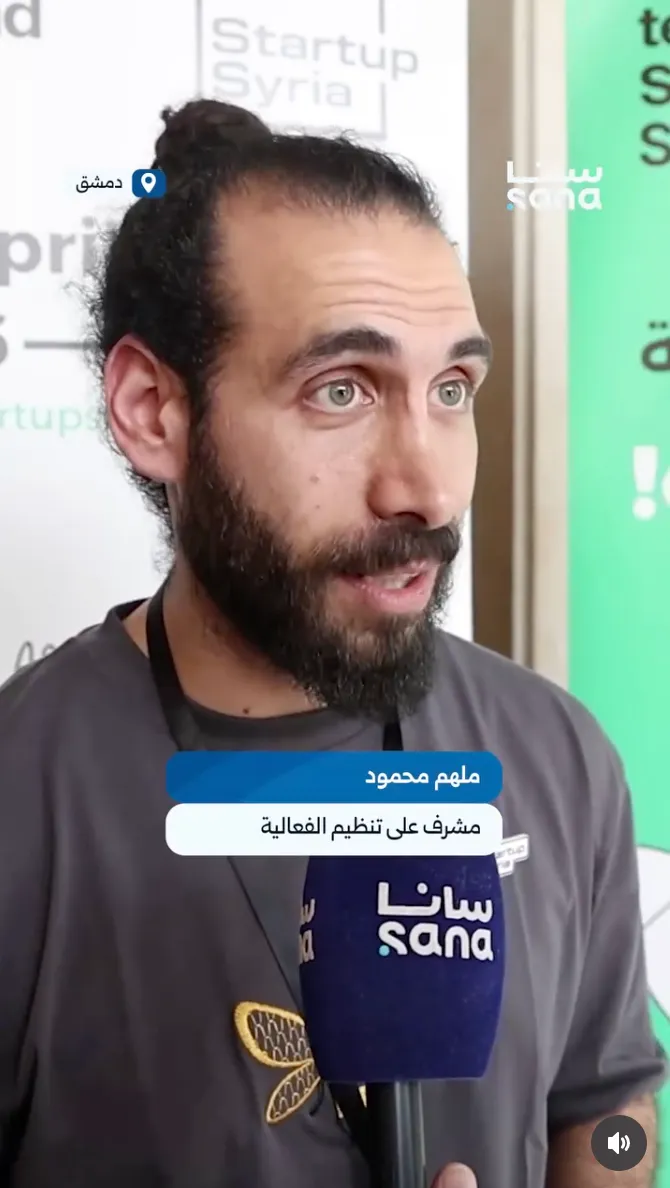 Molham Mahmoud interviewed by SANA on camera, captioned as the event's organising supervisor